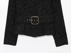 Détail de la veste en tweed noir avec fils dorés et ceinture à boucle dorée carrée