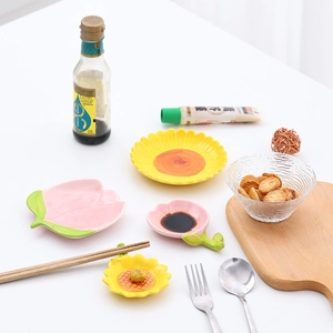 Flower shaped ceramic sauce dishes in sunflower and peach blossom designs on a wooden tray