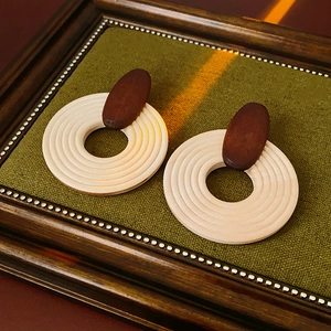 Détail macro de boucles d'oreilles bohèmes en bois aux tons marron et ivoire poli