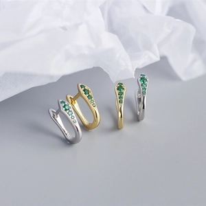 Macro shot of 925 sterling silver snake earrings with green zircon in gold and silver finish
