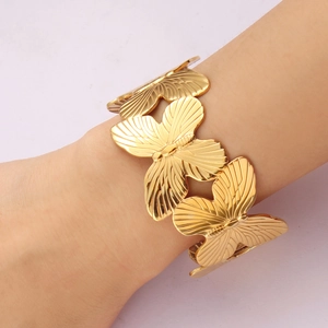Detailed view of an ornate 18K gold-plated titanium steel cuff featuring 3D butterfly designs