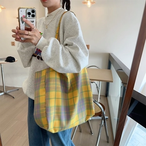 Detailed shot of yellow plaid canvas tote bag used in a casual minimalist outfit