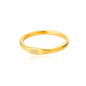 Close-up of minimalist gold ring band featuring clear 999 engraving on flat surface