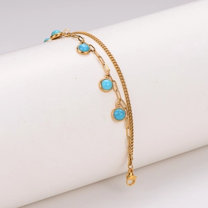 Double-layered golden stainless steel bracelet with turquoise beads on a white display