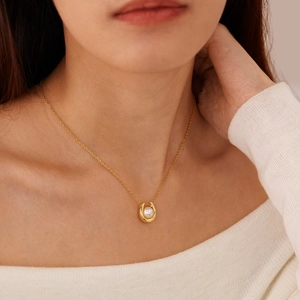 Elegant U-shaped pearl necklace in gold-plated titanium steel worn by a model