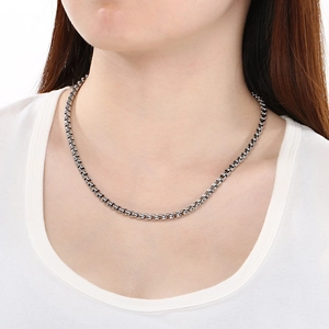 Gros plan d'un collier à chaîne en métal argenté minimaliste porté par un mannequin