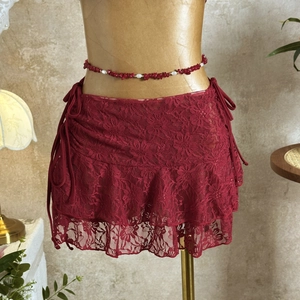 Detail view of dark red floral lace mini cover-up skirt with delicate beaded waist chain