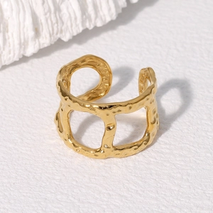 Detailaufnahme des goldenen asymmetrischen Rings mit Hammerschlag-Textur auf Papier