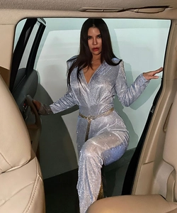 Detail of glittery blue v-neck jumpsuit featuring a sparkling rhinestone waist belt