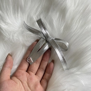 Detail of silver metal bow hair clip with a pink heart-shaped crystal centerpiece
