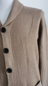 Detailed close-up of khaki knit cardigan featuring shawl collar and large black buttons