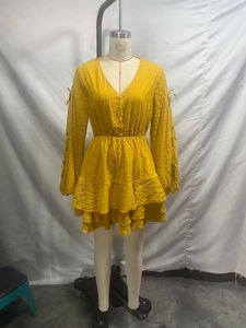 Dettaglio dell'abito giallo con scollo a V, gonna a balze e lacci sulle maniche lunghe