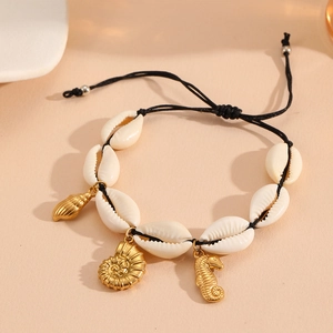 Detail of seashell woven bracelet with starfish, seahorse and nautilus golden charms