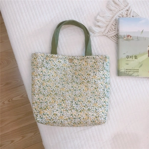 Close-up of floral canvas tote with green straps, vintage button, and rustic props