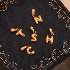 Detailed macro shot of five 18K gold-plated bubble letter charms on a jewelry box