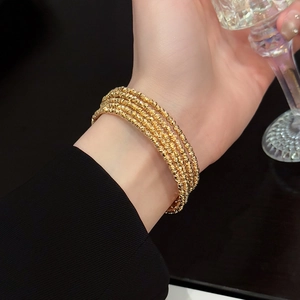 Detailed close-up of a gold-plated five-layer beaded cuff bracelet on a model's wrist