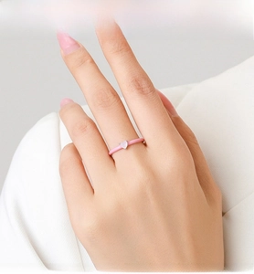 Detail of pink enamel silver ring featuring a heart-shaped zircon on a finger