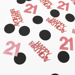 Pink glitter Happy Birthday and 21 confetti scattered on a white party table
