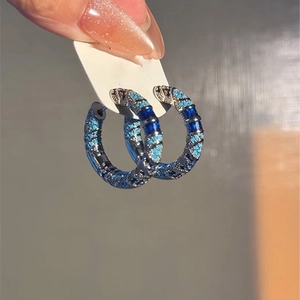 Detail view of vintage hoop earrings with blue zircon and turquoise stones on black metal