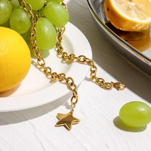 Gold star pendant thick chain necklace on a white plate with fruits decor
