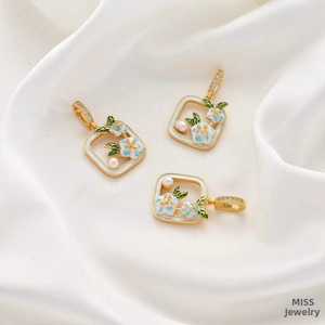 Detail of square enamel flower pendants with natural pearls on white silk fabric