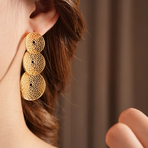 Nahaufnahme goldener dreifacher Kreis-Ohrringe an Model mit elegantem, hohlem Metalldesign