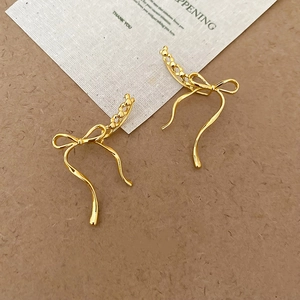Detailed macro shot of gold bow knot earrings with polished finish on textured background