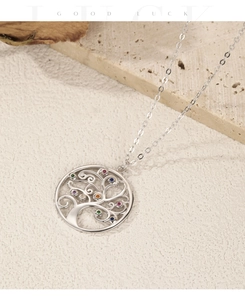 Macro shot of silver Tree of Life necklace with colorful gems on a rustic stone background