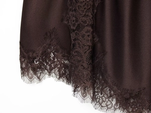 Detailed macro view of dark chocolate satin fabric with delicate eyelash lace trim