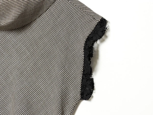 Detailed close-up of houndstooth fabric with intricate black floral lace trim detailing