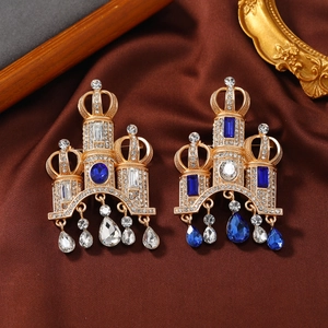 Vintage gold castle brooch with blue rhinestones and tassels on a silk background