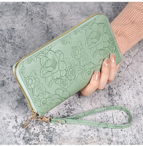 Close-up of floral embossed faux leather on mint green long zipper wallet with hand strap