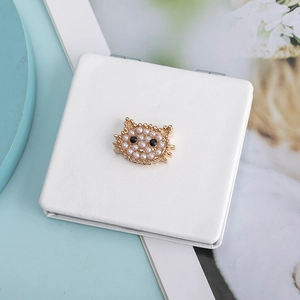 Detail of portable mini square PU leather mirror with pearl and gold cat face decoration