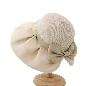 Elegant straw sun hat with mesh bow decoration displayed on a wooden stand