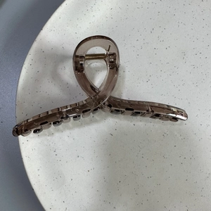 Macro detail of a 13cm transparent taupe hair claw clip with glossy finish and metal spring