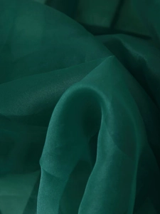 Detaillierte Makroansicht von dunkelgrünem Organza-Stoff mit eleganten Falten