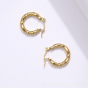 Detail of 18K gold-plated bamboo-textured hoop earrings with a polished metallic finish