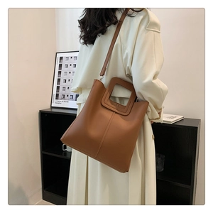 Model wearing a vintage brown matte PU leather bucket tote bag in a minimalist setting