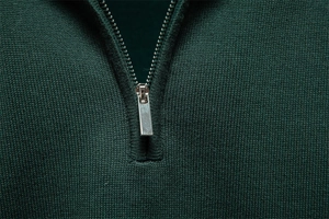 Vue détaillée d'un pull en maille vert foncé avec fermeture éclair en métal argenté