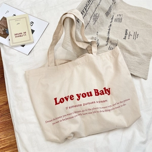 Detail of cream canvas tote bag with bold red Love you Baby print and text