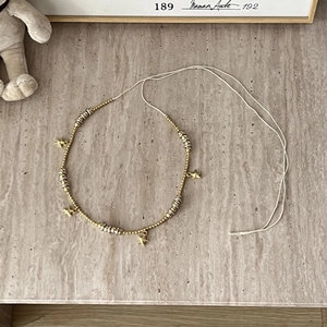 Detail of bohemian braided waist chain with metallic beads and star shaped charms