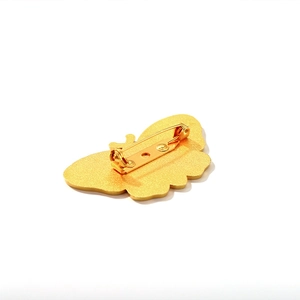 Golden butterfly enamel brooch with secure pin clasp shown from a rear perspective