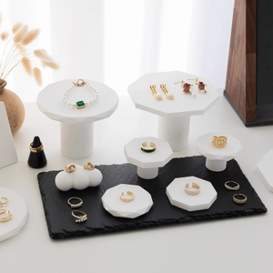 Elegant jewelry display with gold rings, pearl bracelets and earrings on white pedestals