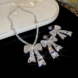 Macro shot of silver bow earrings and necklace set with sparkling trapezoid zircons
