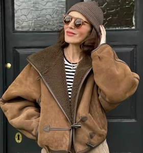 Dettaglio del cappotto in pelle scamosciata marrone con alamari e fodera in montone