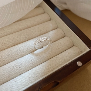 Close-up of double-layered silver ring with bead texture in a wooden jewelry box