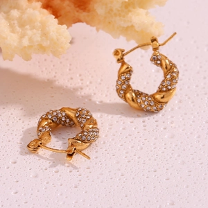 Macro detail of 18K gold plated twisted hoop earrings with sparkling zircon inlay