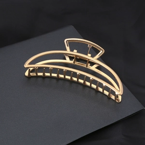 Minimalist gold geometric hair claw clip with crescent design on black background
