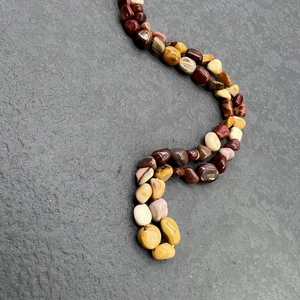 Macro detail of natural irregular jasper stone beads on a stainless steel necklace