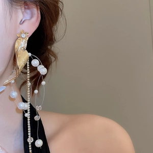 Close-up of elegant gold leaf earrings with pearl tassels and shimmering crystal flowers